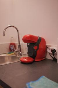 a red mixer sitting on a counter next to a sink at CinémaRoom Béziers in Béziers