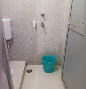 een douche met een blauwe emmer in een badkamer bij Sri Hotel Ganga in Patna