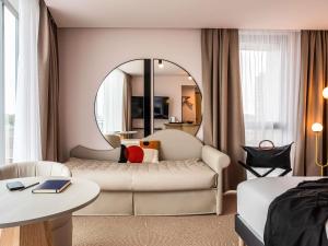 Una sala de estar con un sofá blanco y un espejo. en Mercure Dunkerque Centre Gare, en Dunkerque 112 fotos más