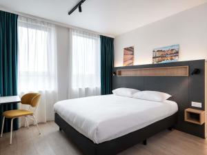 Un dormitorio con una cama grande y una silla. en Adagio Access Gent Centrum Dampoort, en Gante