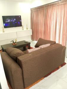 a living room with a brown couch and a tv at Millenium Manor Executive Homes in Centurion