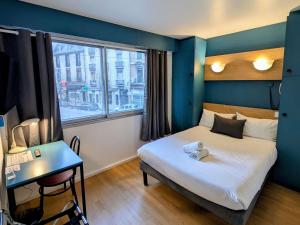 Un dormitorio con una cama y un escritorio y una ventana. en greet hotel Grenoble Centre Gare, en Grenoble