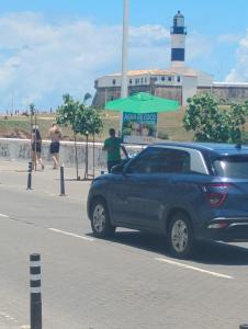een blauwe vrachtwagen geparkeerd naast een strand met een vuurtoren bij Pousada & hostel Guedes in Salvador