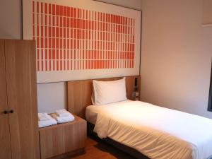 a bedroom with a bed and a cabinet with towels at ibis Chiang Mai Nimman Journeyhub in Chiang Mai