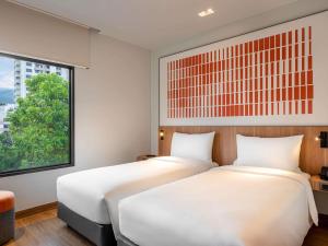 two beds in a room with a window at ibis Chiang Mai Nimman Journeyhub in Chiang Mai +31 photos