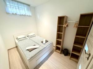 a white bedroom with a bed and a book shelf at DowntownKate in Debrecen