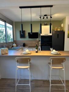 a kitchen with a counter with two bar stools at Aux Trompettes Violettes in Amiens