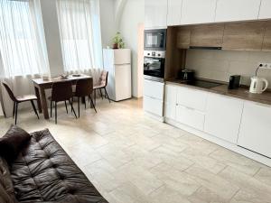 a kitchen with white cabinets and a table with chairs at DowntownKate in Debrecen +8 photos