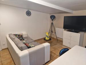 a living room with a couch and a flat screen tv at Gîte Kerlosvézan, à la campagne, proche mer in Lampaul-Ploudalmézeau