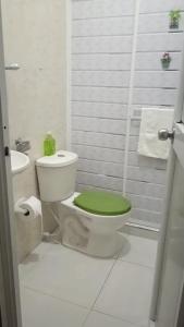 a bathroom with a toilet with a green lid at Casa Zoe - Habitación Económica en Casa Familiar in Guayabal