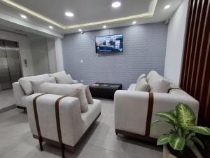 a living room with couches and a flat screen tv at Hotel CGH Travel INN Airport in Bogotá