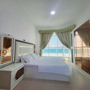 a bedroom with a large bed and a large window at Beachfront Holiday Homes in Ajman 