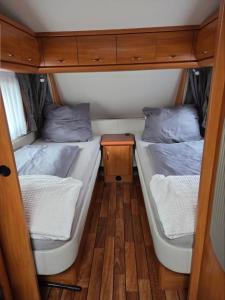 Dos camas en una habitación pequeña con una mesa. en Feriencamp Familie Lange - Primc, en Radensdorf