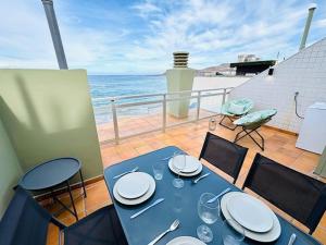 a blue table and chairs on a balcony with the ocean at First-Line Las Canteras Beach in Las Palmas de Gran Canaria