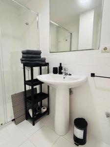 a white bathroom with a sink and a mirror at First-Line Las Canteras Beach in Las Palmas de Gran Canaria