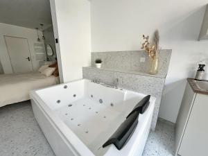 eine weiße Badewanne in einem Badezimmer mit einem Bett in der Unterkunft L'intemporel - Balneo, Cozy, Romantic in Lambersart + 21 Fotos