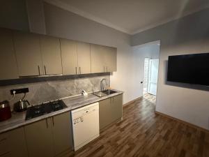 a kitchen with white cabinets and a flat screen tv at Atom Haus in Mkhchʼyan
