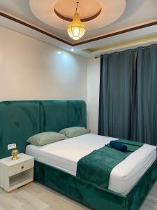 a bed with a green headboard in a room at KSyiimmo Signature aéroport Marrakech in Marrakesh