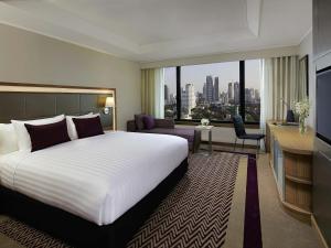 Una habitación de hotel con una cama grande y una ventana grande. en Grand Mercure Bangkok Atrium, en Bangkok