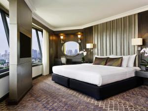 Un dormitorio con una cama grande y una ventana grande. en Grand Mercure Bangkok Atrium, en Bangkok