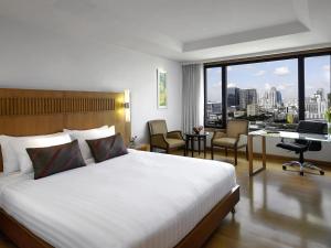 Habitación de hotel con cama y escritorio con vistas. en Grand Mercure Bangkok Atrium, en Bangkok