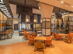 Un vestíbulo con mesas y sillas y un restaurante. en ibis Thane - An Accor Brand, en Thane