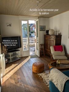 a living room with a couch and a tv at Spacieux apt avec terrasse proche plage in Criel-sur-Mer