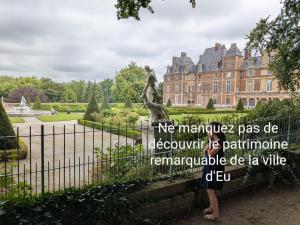 a woman standing in front of a building with a statue at Spacieux apt avec terrasse proche plage in Criel-sur-Mer