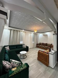 a living room with green couches and a table at KSyiimmo Signature aéroport Marrakech in Marrakesh