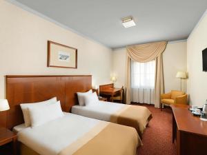 a hotel room with two beds and a desk at Mercure Szekesfehervar Magyar Kiraly in Székesfehérvár