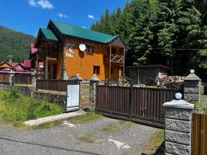 a wooden house with a fence and a gate at Лісова тиша Дворівневий Люкс in Synevyrsʼka Polyana