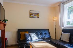 ロンドンにあるCozy 4-Bed House in Wimbledonのリビングルーム(黒革のソファ付)