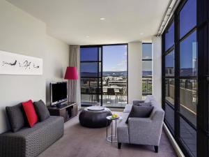 a living room with two chairs and a tv at Mantra Hindmarsh Square in Adelaide