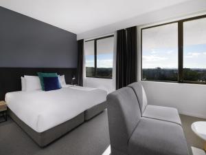 a hotel room with a bed and a chair at Mantra MacArthur Hotel in Canberra