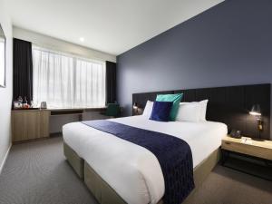 a bedroom with a large bed with a blue wall at Mantra MacArthur Hotel in Canberra