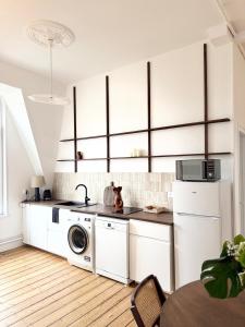 Una cocina con gabinetes blancos y lavadora y secadora. en Halluin Marthe Nollet, en Halluin