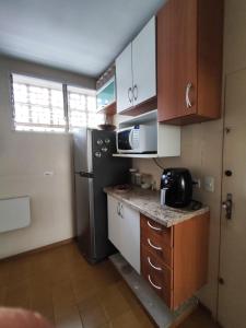 a small kitchen with a black refrigerator and cabinets at 2U TOUR - Guarujá perfeito in Guarujá