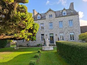 a large stone house with a statue in the yard at GÎTE L'industriel, appartement privé en Duplex, à 10 minutes des plages in Lanhouarneau