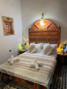 een slaapkamer met een groot bed met een houten hoofdeinde bij Fes Dar Riad - Stay Timeless in Fès