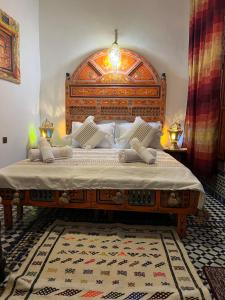 een slaapkamer met een groot bed met een houten hoofdeinde bij Fes Dar Riad - Stay Timeless in Fès