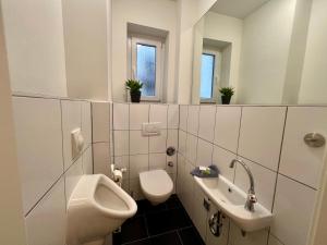 a bathroom with a toilet and a sink and a urinal at Ferienwohnungen im Zentrum von Mönchengladbach in Mönchengladbach +27 photos