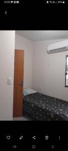 a small bedroom with a bed and a wooden door at Pousada Aconchego in Sidrolândia