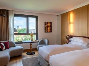 a hotel room with two beds and a window at Le Louise Hotel Brussels - MGallery Collection in Brussels