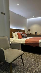 a bedroom with a large bed and a chair at Hotel La Caleche in Durbuy