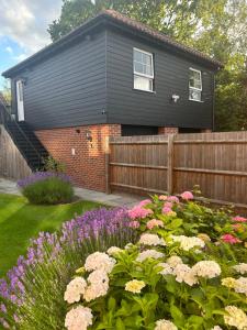 a black house with a garden of flowers at Stansted Coach House - Apartment Hotel in Elsenham