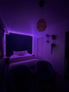ein lila Schlafzimmer mit einem Bett und einer violetten Beleuchtung in der Unterkunft Studio dans le cœur de Mulhouse in Mulhouse