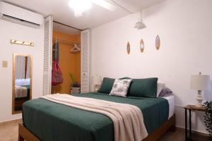 a bedroom with a bed with green sheets at BeachBums Hideaway in Luquillo