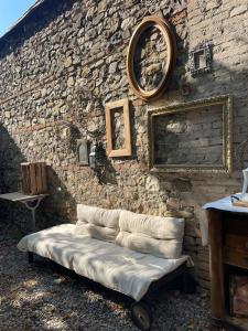 a couch against a stone wall with a clock on it at Una Casa Bottega in Barco