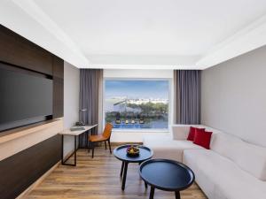 a living room with a white couch and a large window at Novotel Jaipur Convention Centre in Jaipur