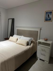 a bedroom with a white bed with a night stand at Caleta View Marítimo in Puerto Madryn +22 photos